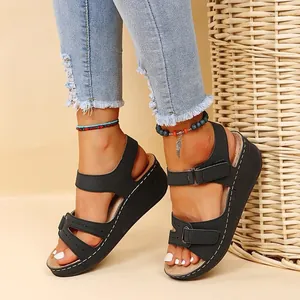 Side view detail of black wedge sandals with contrast stitching and velcro straps
