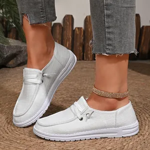 Close-up detail of women's grey canvas slip-on loafers with textured fabric and white sole