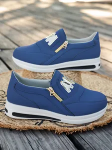 Detailansicht von blauen Plateau-Sneakern mit goldenen Reißverschlüssen und M-Logo