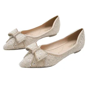 Elegant champagne pointed toe flat shoes featuring decorative bow and shimmering crystals