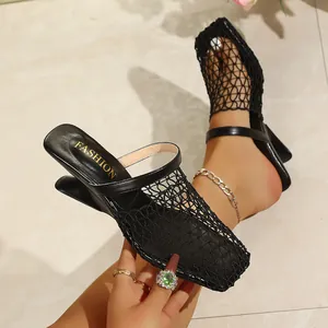 Détail de près des mules à talons compensés noirs avec un design chic en maille ajourée