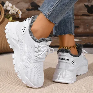 Close-up van witte wintersneakers met bontvoering voor dames op een kleed