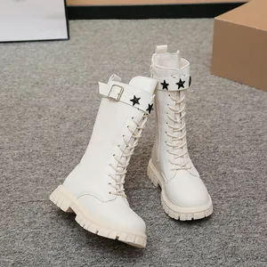 Detail view of stylish cream girl's Martin boots with black star studs and lug sole