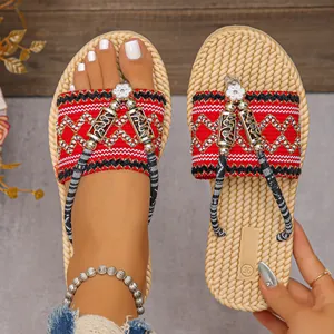 Detalle de las chanclas boho de paja con tiras bordadas rojas y adornos de flores