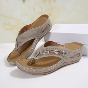 Vista detallada de chanclas con cuña grises con patrones láser y elegantes detalles dorados