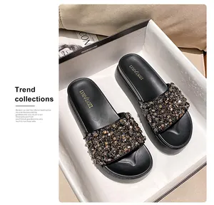 Detailweergave van luxe zwarte plateau-slippers met kralenstrass-band in witte doos