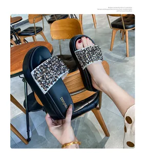 Detailopname van stijlvolle zwarte platformslippers met fonkelende bandjes met strasstenen