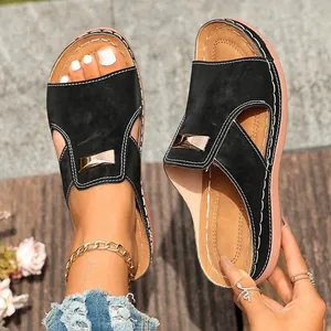 Sandales à talons compensés noires avec boucle métallique et coutures contrastées.