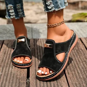 Gros plan de sandales compensées noires pour femmes avec boucle dorée