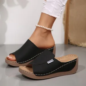 Primer plano de sandalias negras con cuña y punta abierta con suelas de plataforma
