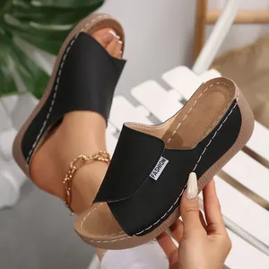 Vista detallada de sandalias de cuña negras con etiqueta de moda y costuras blancas