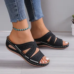 Primer plano de sandalias de cuña negras con calados y costuras blancas decorativas