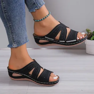 Detalle de elegantes sandalias de cuña negras con patrones calados con láser en los pies