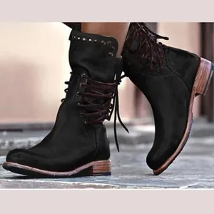 Close-up detail of black mid-calf boots featuring rear lacing design and metal stud accents