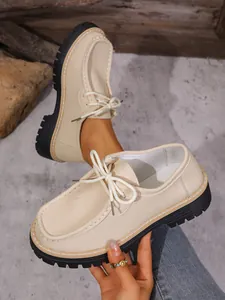 Gros plan sur des mocassins à plateforme beiges avec coutures rétro et lacets