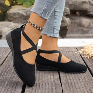 Gros plan sur des chaussures compensées en daim noir à brides croisées élastiques.
