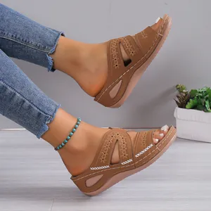 Vista detallada de sandalias de cuña marrones para mujer con calados y costuras blancas.