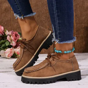 Détail de chaussures rétro en daim marron à lacets avec surpiqûres et semelle épaisse.
