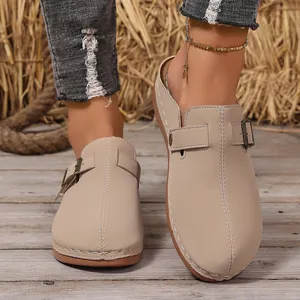 Detail view of women's beige closed-toe mules with buckle strap and visible stitching
