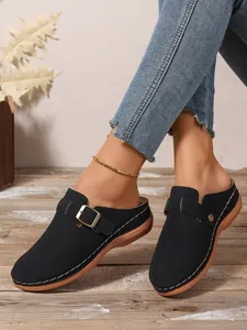 Close-up of black women's platform mule sandals with buckle and white stitching