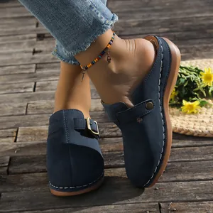 Detailed view of women's navy blue wedge mules with stitching and buckle accent