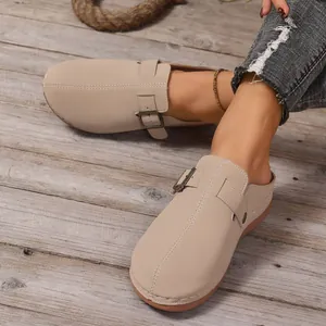 Casual beige closed-toe clogs for women featuring buckle strap detail on wood floor