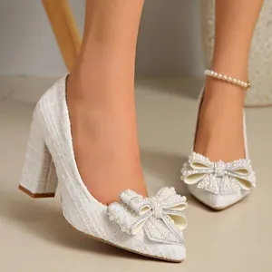 Detailed view of white tweed block heel pumps with elegant pearl bow and pointed toe