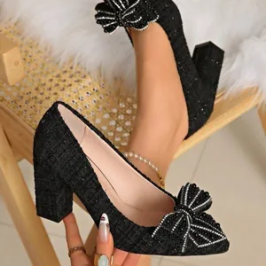Close-up detail of elegant black tweed pointed toe pumps with rhinestone bow and block heel