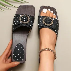 Close-up of polka dot sandals with gold metal buckle and wood grain platform sole.
