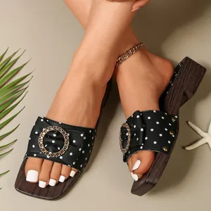 Close-up of retro polka dot sandals with decorative metal ring and wood grain platform sole.