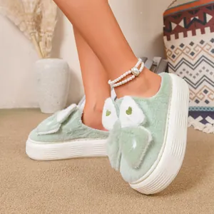 Dettaglio di pantofole platform in peluche verde con fiocco decorativo bianco e verde