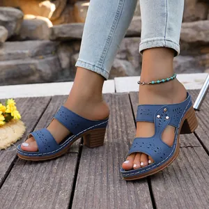 Detailed view of blue hollow-out block heel sandals with white stitching accents.