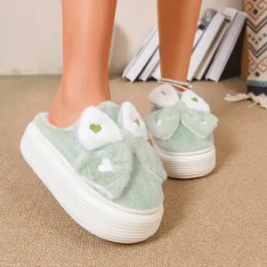 Dettaglio di pantofole platform in peluche verde chiaro con fiocco e cuore carini