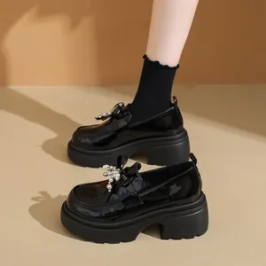 Λεπτομερής προβολή των μαύρων λουστρίνι loafers με πλατφόρμα και κομψό μαργαριταρένιο φιόγκο