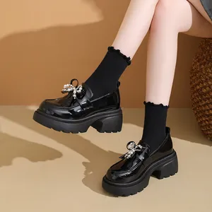 Λεπτομερής όψη μαύρα λουστρίνι loafers με πλατφόρμα και έναν διακοσμητικό φιόγκο πέρλα