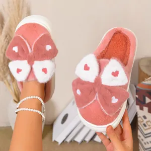 Dettaglio di pantofole platform in peluche rosa con un grande fiocco e cuori