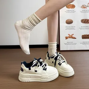 Vue détaillée de baskets compensées blanches avec accents bleu et semelles épaisses.