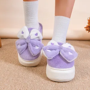 Dettaglio di simpatiche pantofole in peluche viola con fiocco grande e cuori