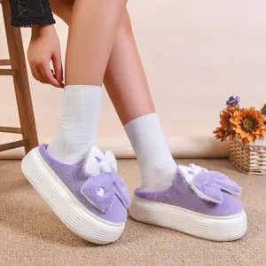 Dettaglio di pantofole di peluche viola con fiocco a coniglio e suola spessa platform.