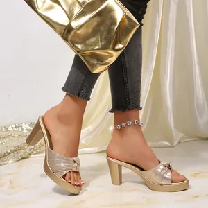 Vista lateral de estas elegantes sandalias tipo mule doradas con tacón grueso y nudo