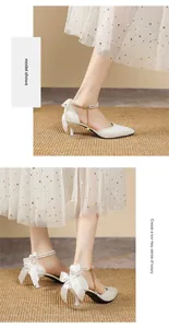 Detail view of white pointy heels with pearl ankle strap and elegant bow on the back.
