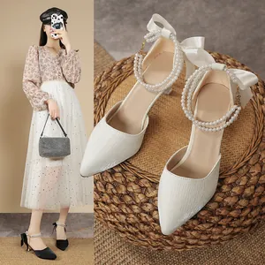 Detail view of elegant French pointed toe heels with pearl ankle strap and silk bow
