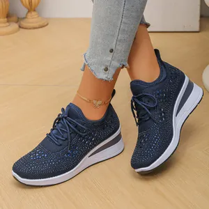 Primer plano detallado de zapatillas con cuña de punto azul con pedrería y diseño de cordones