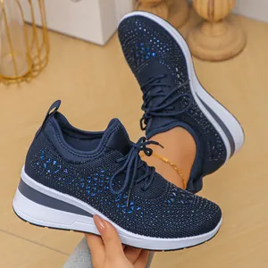 Primer plano de zapatillas azules transpirables de punto con adornos de diamantes.