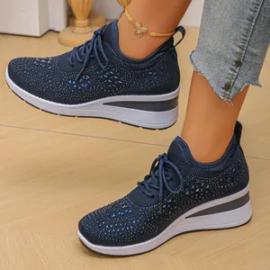 Detalle de zapatillas con cuña azul marino para mujer con tejido de punto y pedrería.
