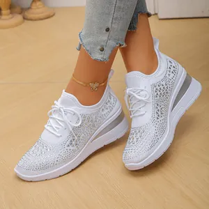 Primer plano de zapatillas blancas de cuña para mujer con pedrería y malla transpirable.