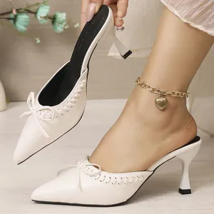 Elegant white pointed-toe kitten heel mules featuring a chic bow and leather texture