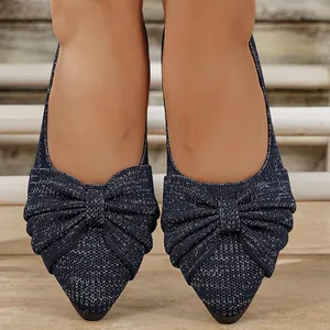 Nahaufnahme von dunkelblauen Glitzer-Ballerinas aus Strick mit großer Zierschleife.