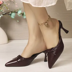 Detailed macro view of burgundy pointed toe mules with delicate bow and chic woven trim
