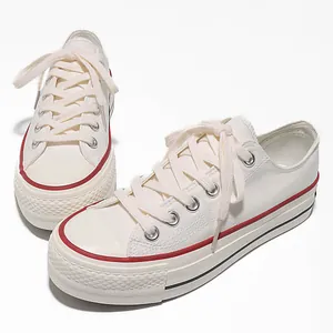 Sneakers platform basse in tela bianca con classiche strisce rosse e nere laterali.